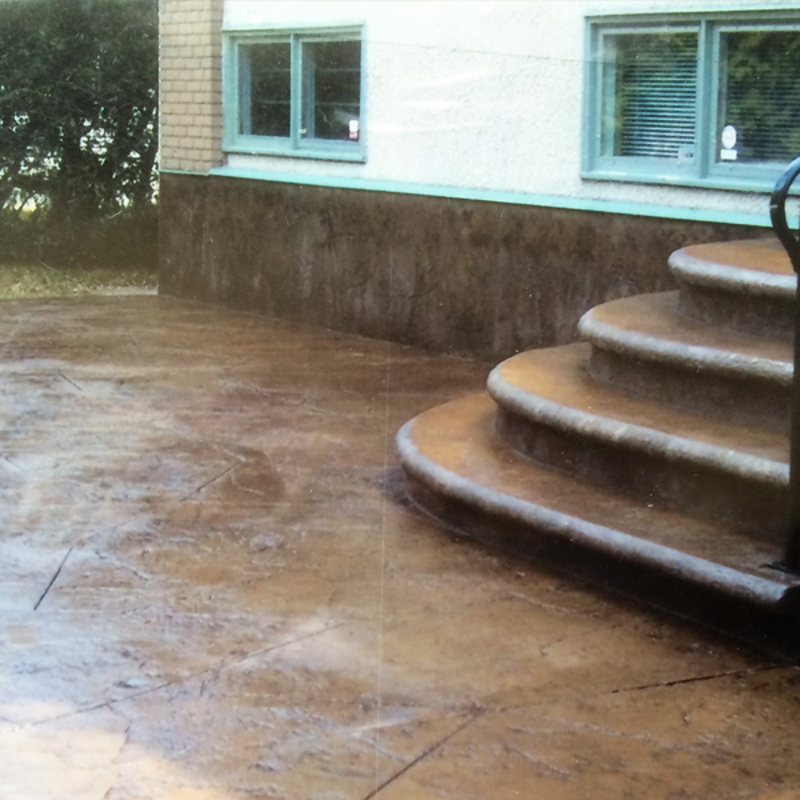 colored stamped concrete back patio with staircase